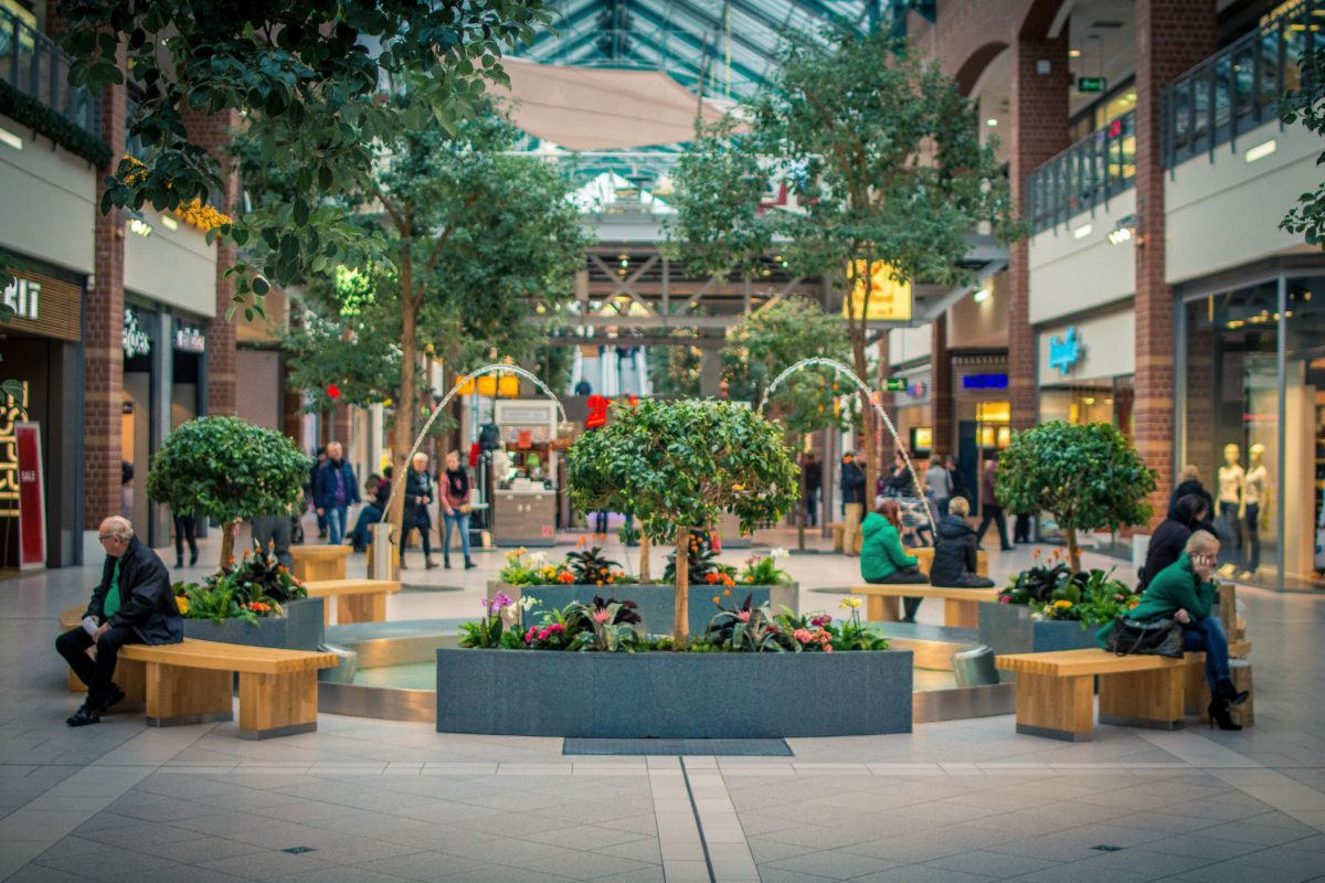 People sitting in a landscaped arbor in the middle of a commercial shopping center